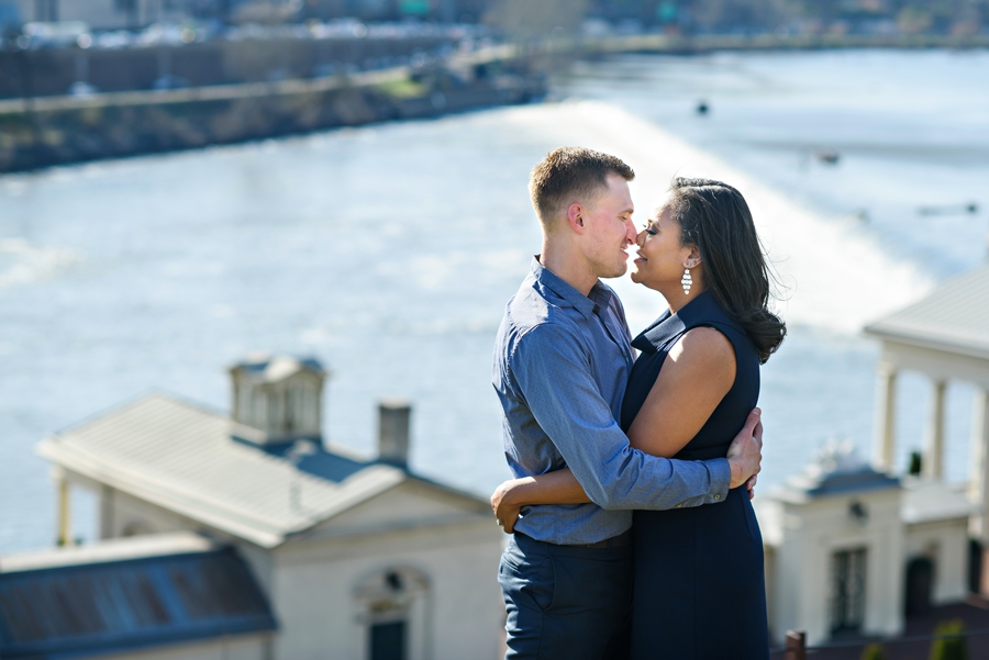 A couple kiss outside of the Philadelphia Art Museum with the Schuylkill River in the background.